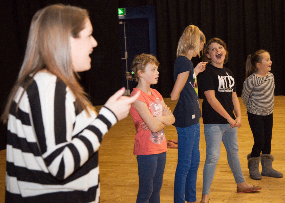 GB, WALES. Blackwood Miners Institute. Artspark! drama group warm up for musical theatre workshop with Gemma Woolley. 2014. © Kate Mercer / https://katemercer.co.uk